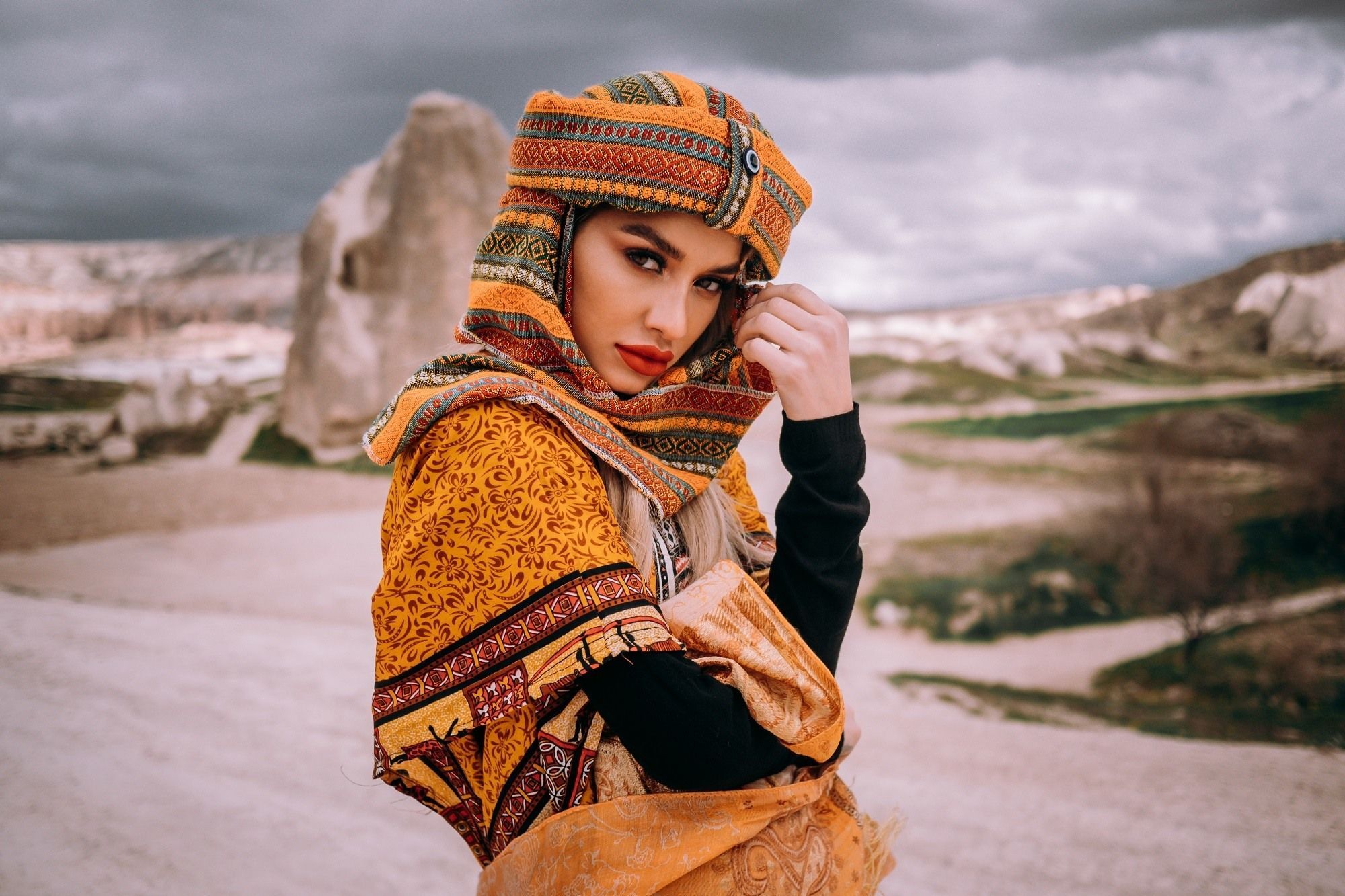 Wanita memakai scarf bermotif maroko di padang pasir.