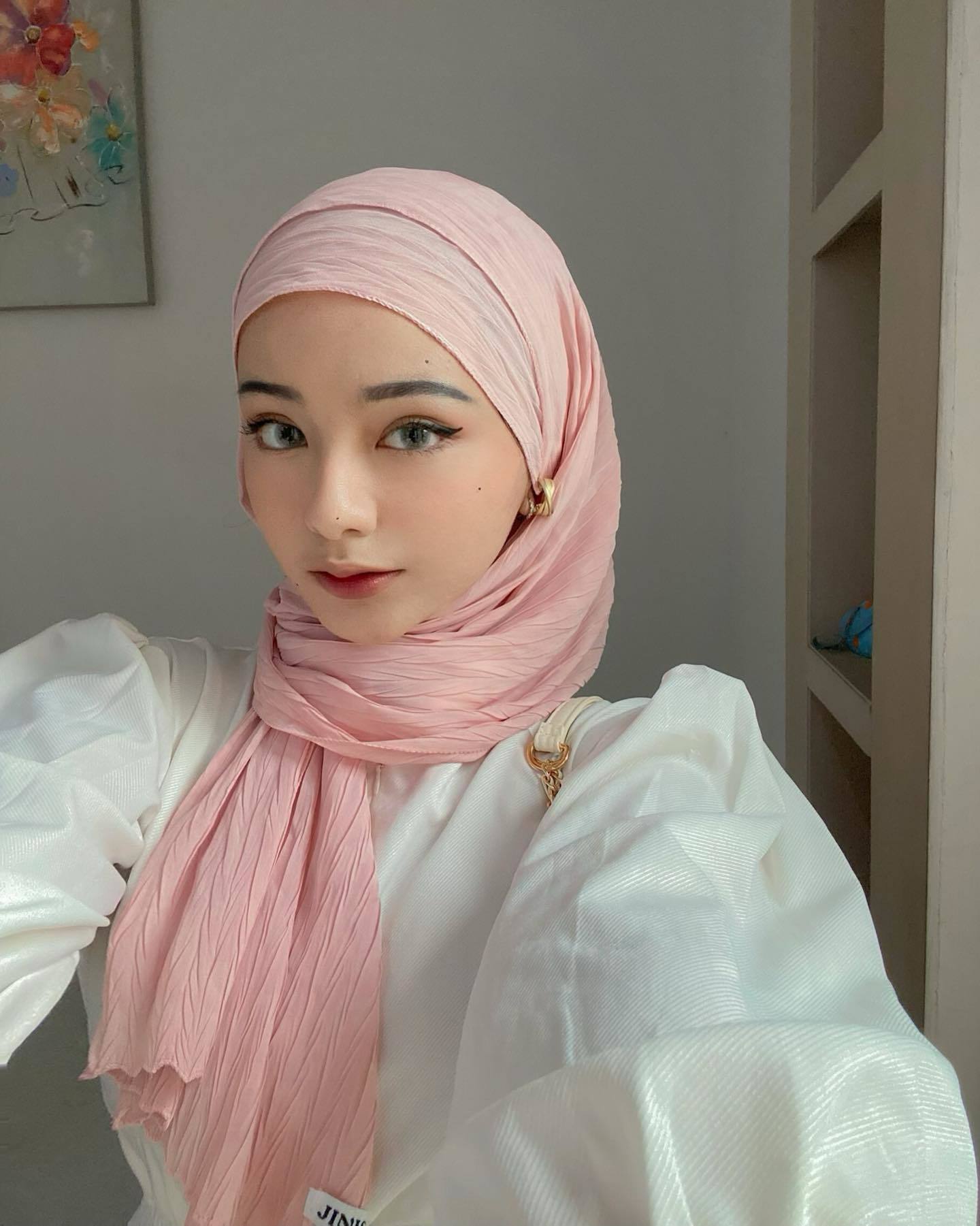 Wanita Indonesia dengan gaya hijab pashmina crinkle warna soft pink.