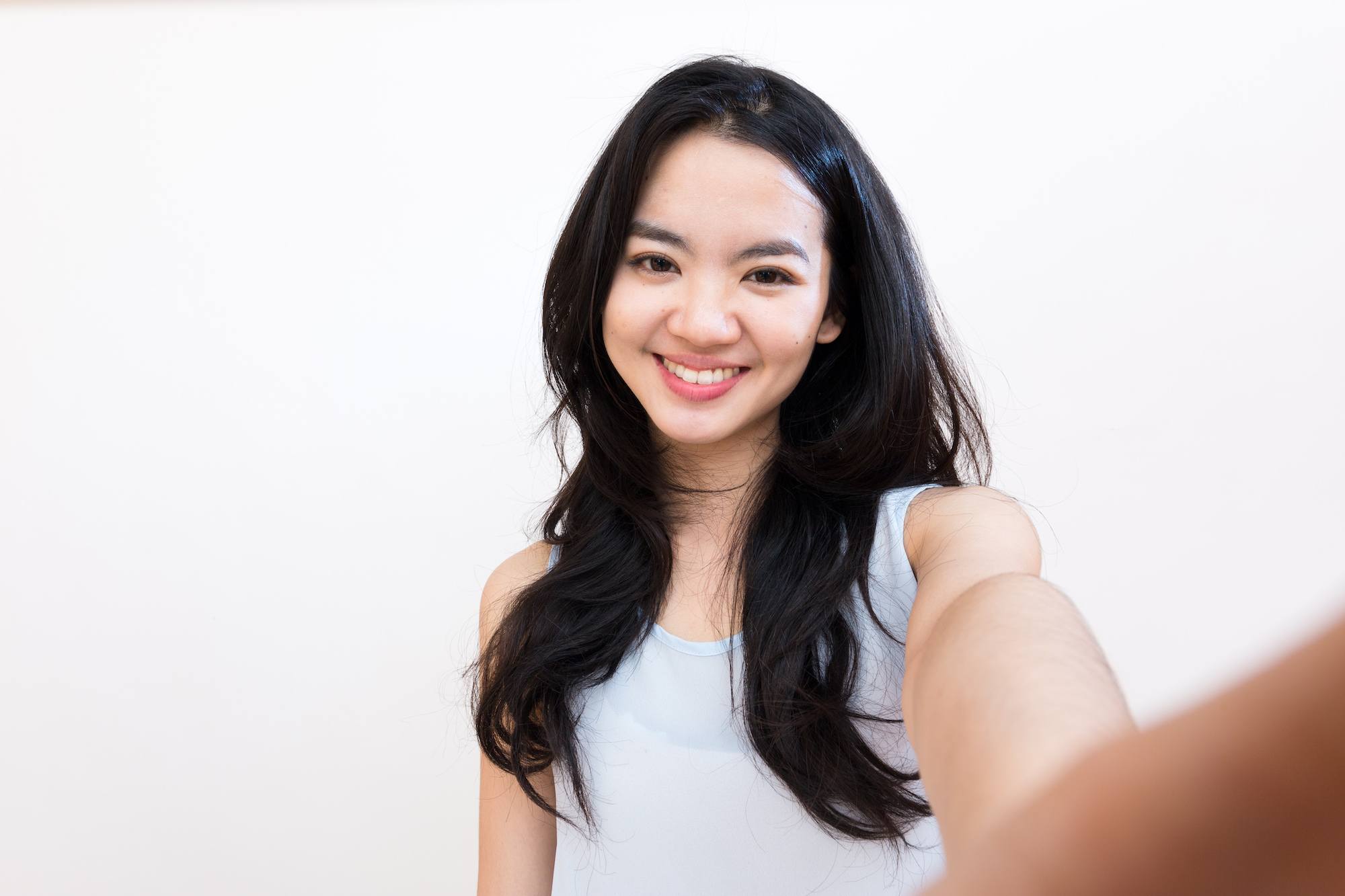 Wanita asia dengan rambut panjang melakukan swafoto