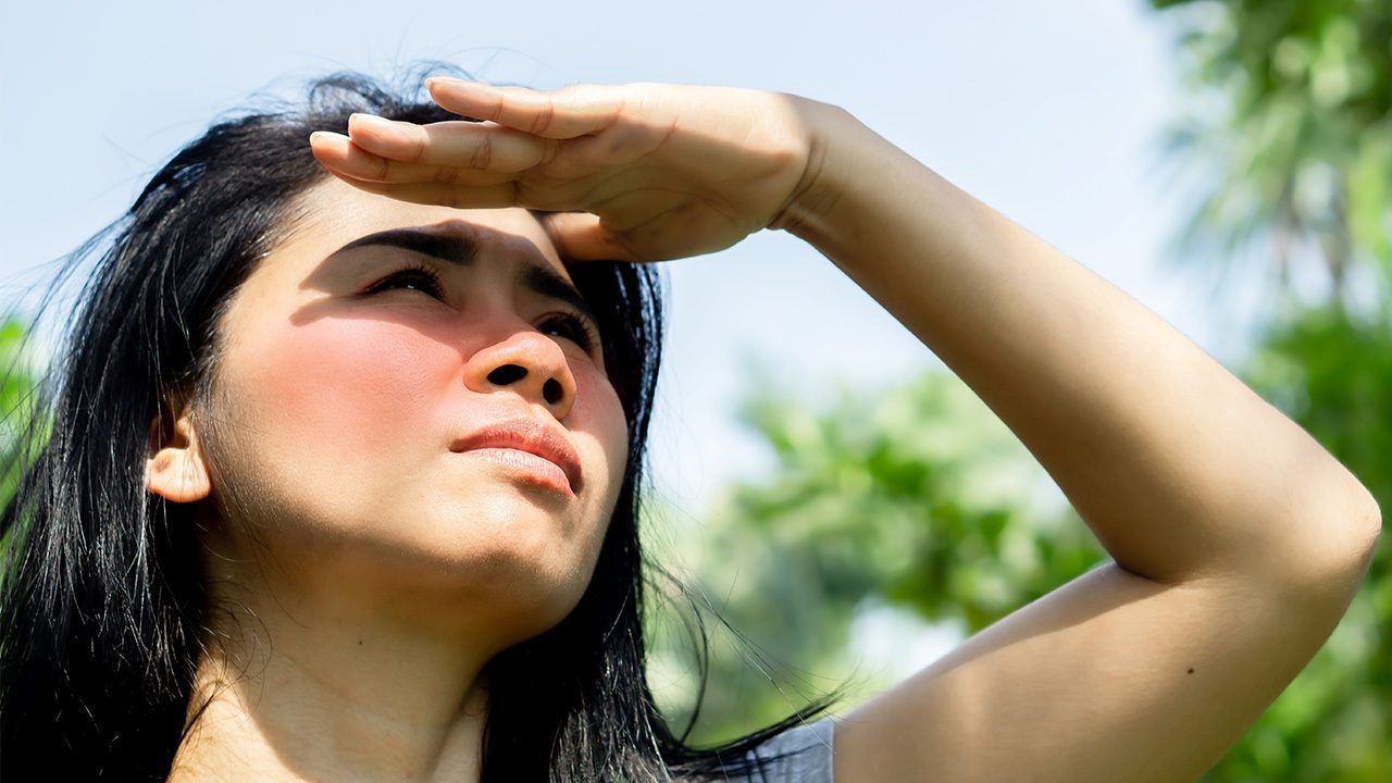 wanita asia sedang menutupi wajah karena sinar matahari yang terik