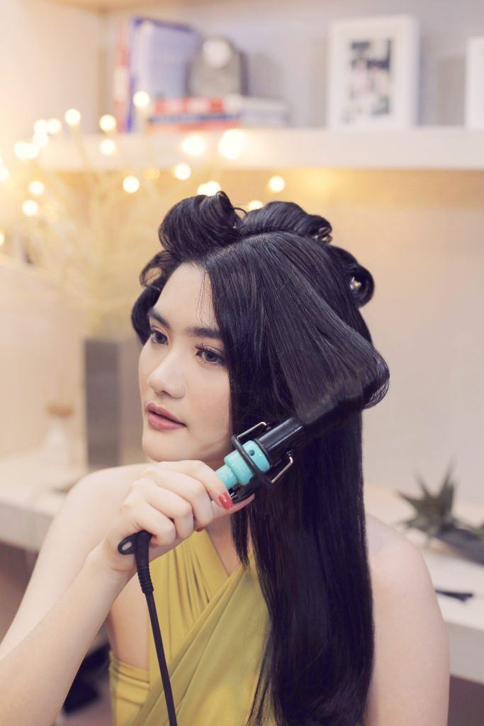 Wanita asia mengeriting rambut dengan curling iron