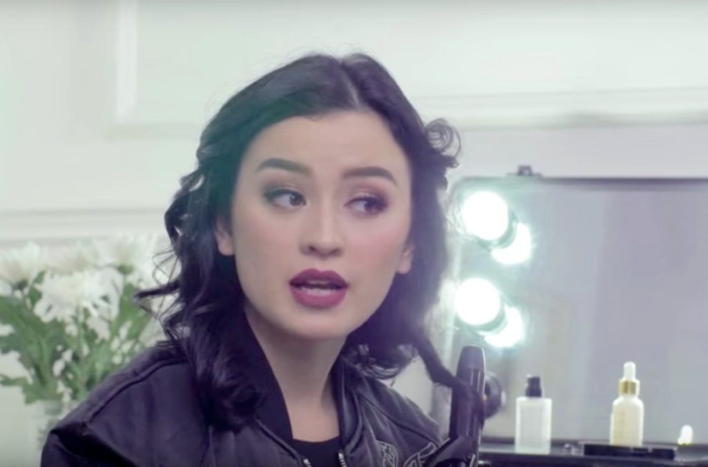 Kimberly Ryder dengan warna rambut hitam sedang mengeriting rambut