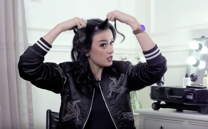 Kimberly Ryder dengan rambut warna hitam sedang mengepang rambut