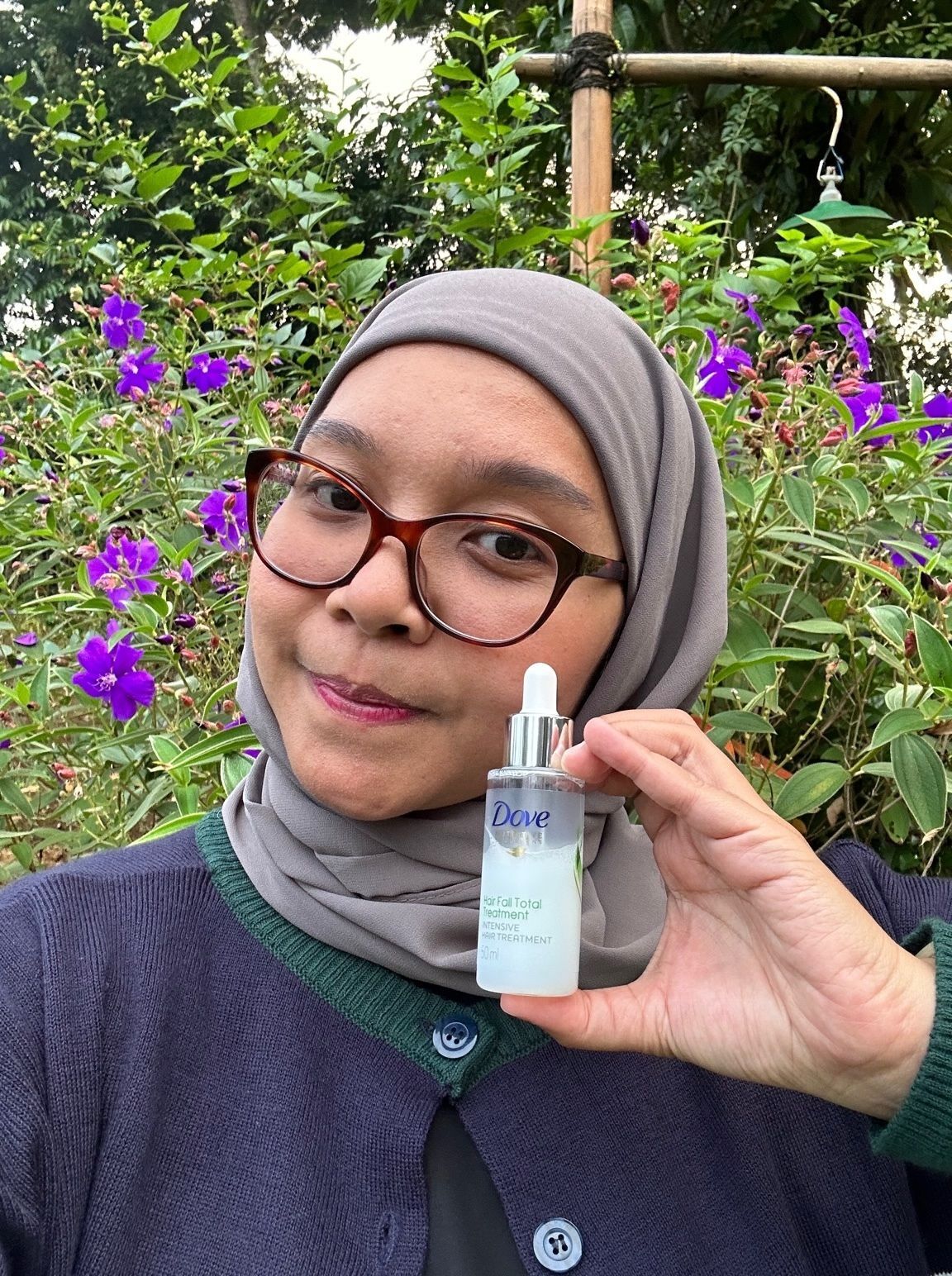 Editor All Things Hair, Mestika sedang memegang botol Dove Tonik Rambut untuk Perawatan Rambut Rontok.