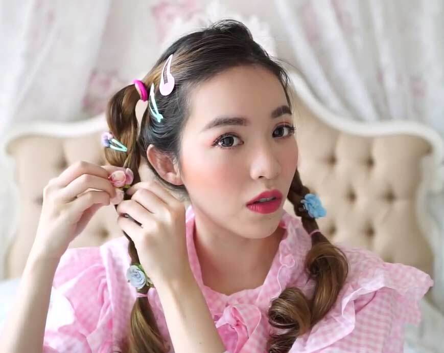 ผู้หญิงเอเชีย หันหน้า ติดกิ๊บสีสดใส บนเปียสองข้าง 