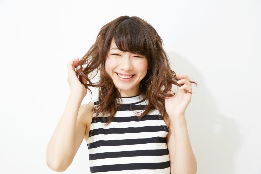 ผู้หญิงญี่ปุ่น ผมดัดยาวประบ่า กำลังจับผมทั้งสองข้าง