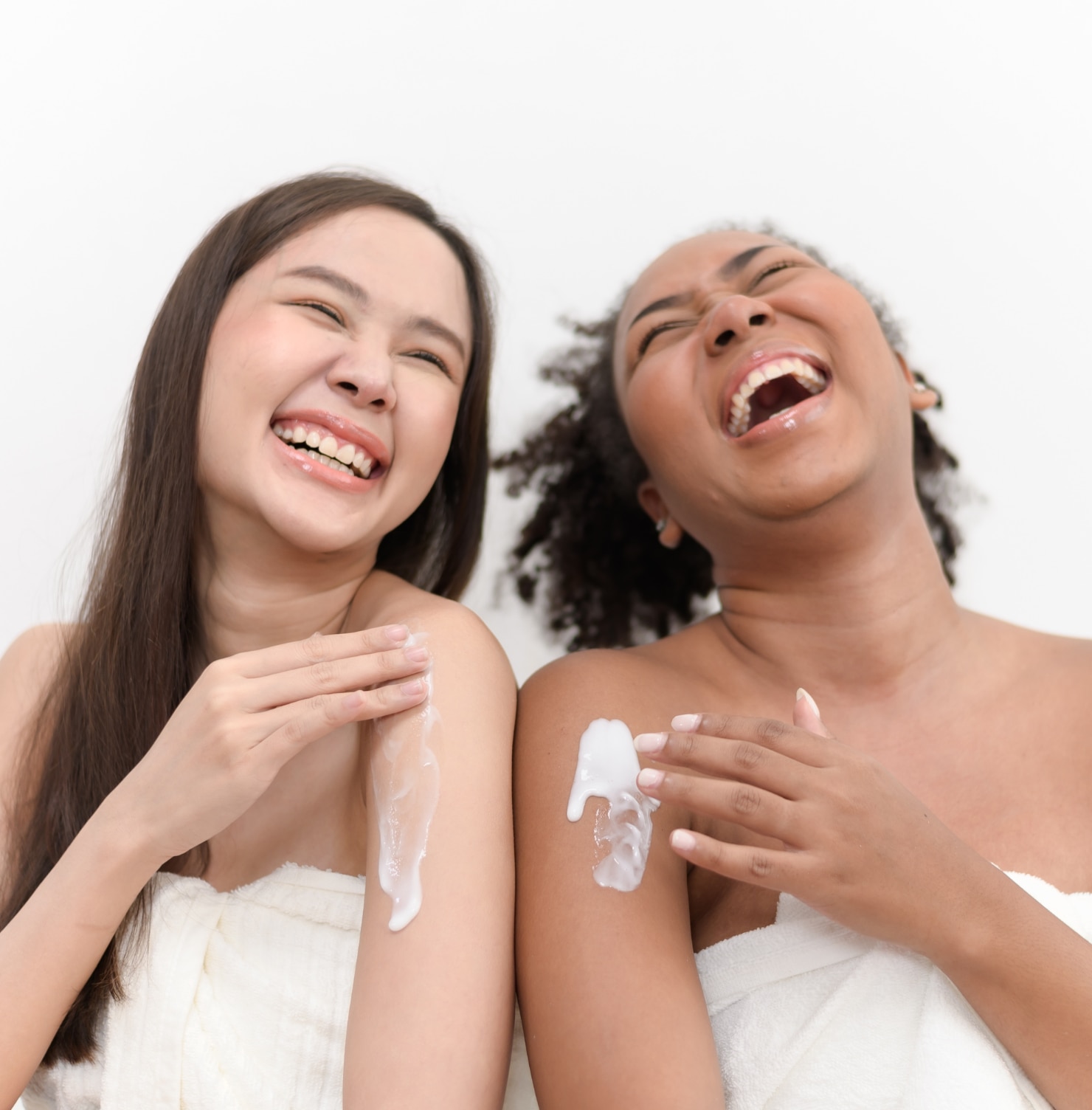 ผู้หญิงสองคน ผิวขาว เอเชีย และผิวคล้ำ แอฟริกัน ทาโลชั่น ร่าเริง