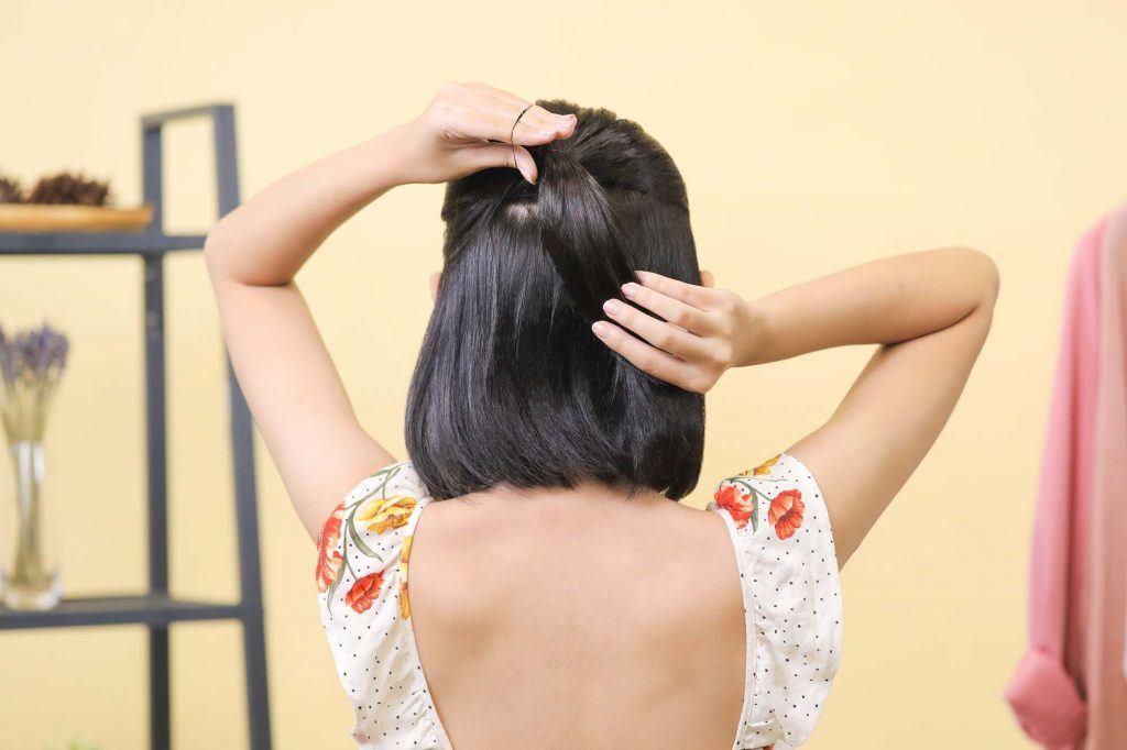 ผู้หญิงเอเชียผมสั้นสีดำหน้าม้าตรง กำลังมัดผม