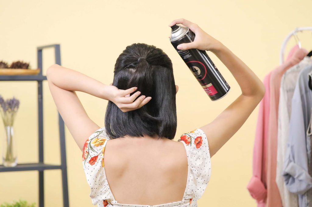 ผู้หญิงเอเชียผมสั้นสีดำหน้าม้าตรง กำลังฉีดสเปรย์