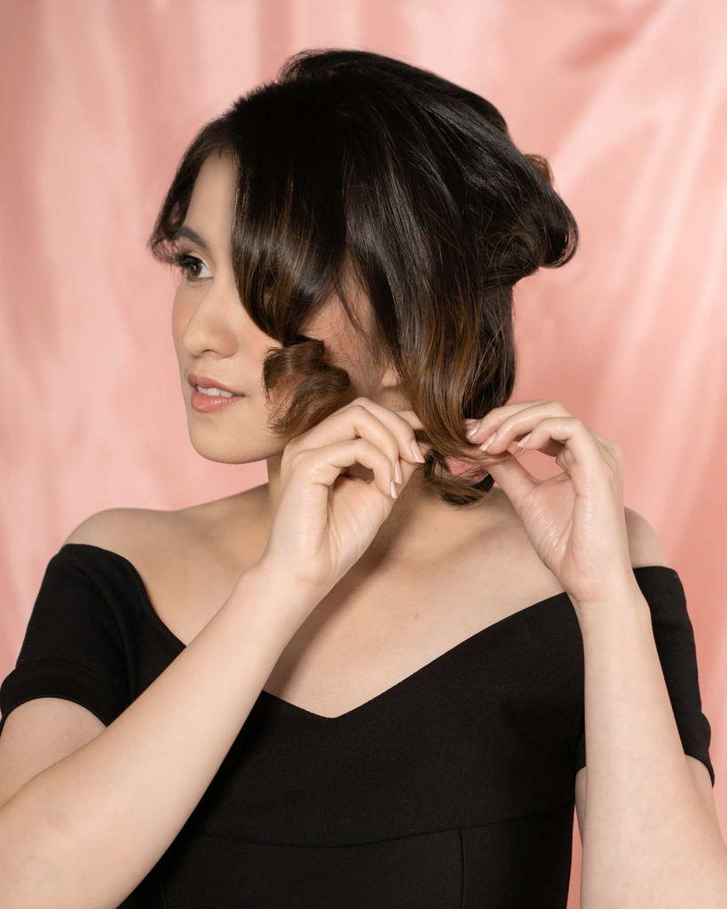 ผู้หญิงเอเชียผมสั้นสีน้ำตาลเข้ม กำลังดัดผมลอนวินเทจ