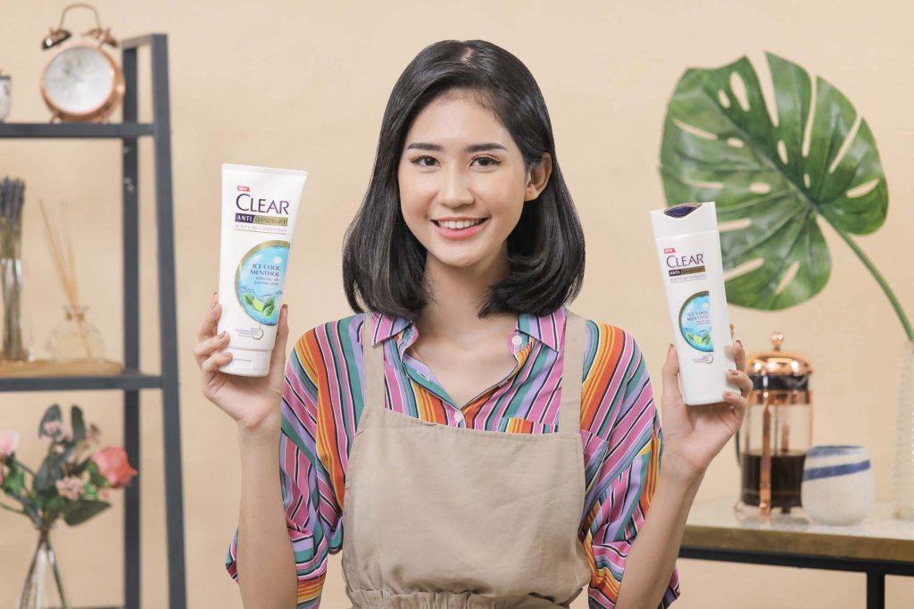 ผู้หญิงเอเชียผมสั้นสีดำ กำลังถือขวดแชมพูและครีมนวดผม