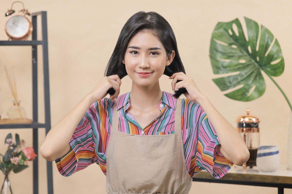 ผู้หญิงเอเชียผมสั้นสีดำ กำลังจับผมสองข้าง