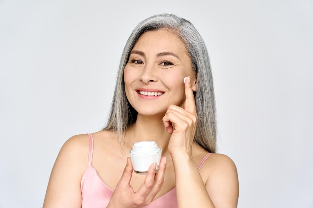 ผู้หญิงเอเชีย วัยกลางคน กำลังทาครีมบำรุงผิว