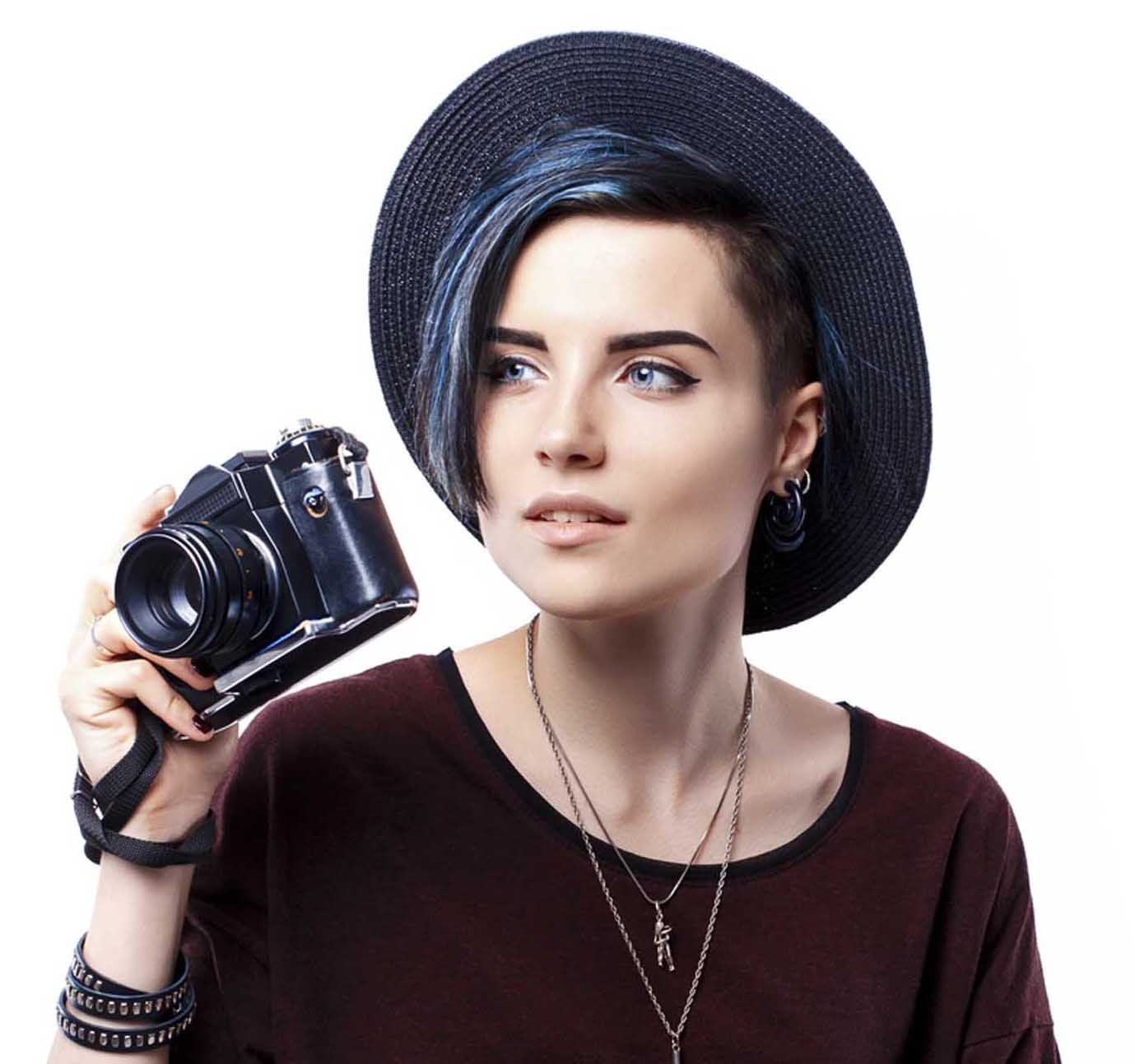 Portrait of smiling blue-haired girl in hat taking shot with film camera.Isolated