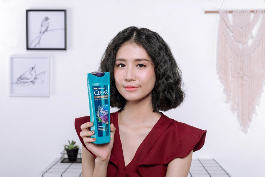 ผู้หญิง เอเชีย ผมสั้นหยักศก ถือ ขวดแชมพู