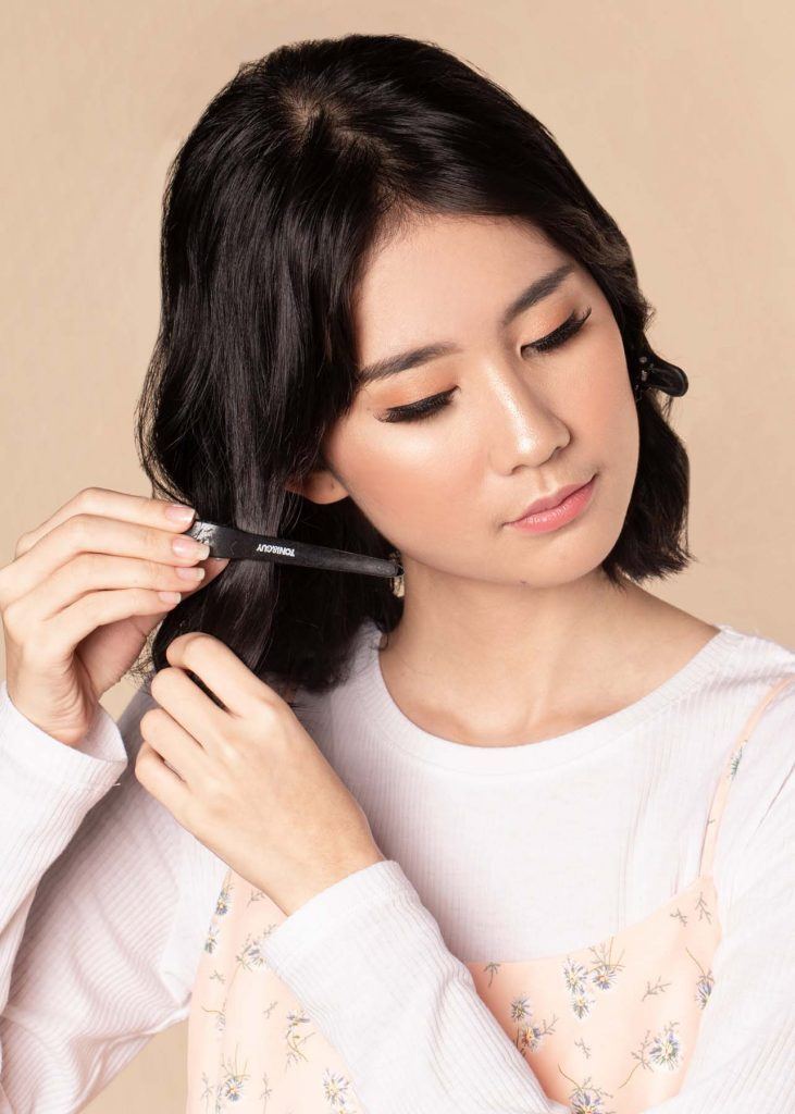 ผู้หญิงเอเชียผมสั้น ใส่เสื้อสีชมพูอ่อน กำลังติดกิ๊บ