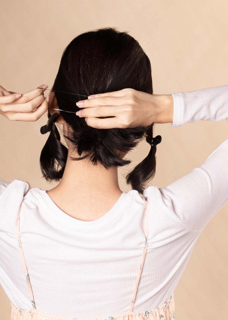 ผู้หญิงเอเชียผมสั้น ใส่เสื้อสีชมพูอ่อน กำลังเกล้าผม