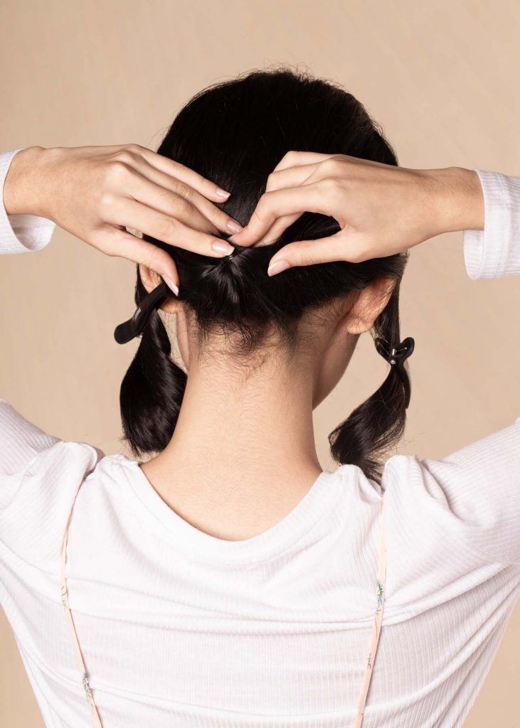 ผู้หญิงเอเชียผมสั้น ใส่เสื้อสีชมพูอ่อน กำลังเกล้าผม