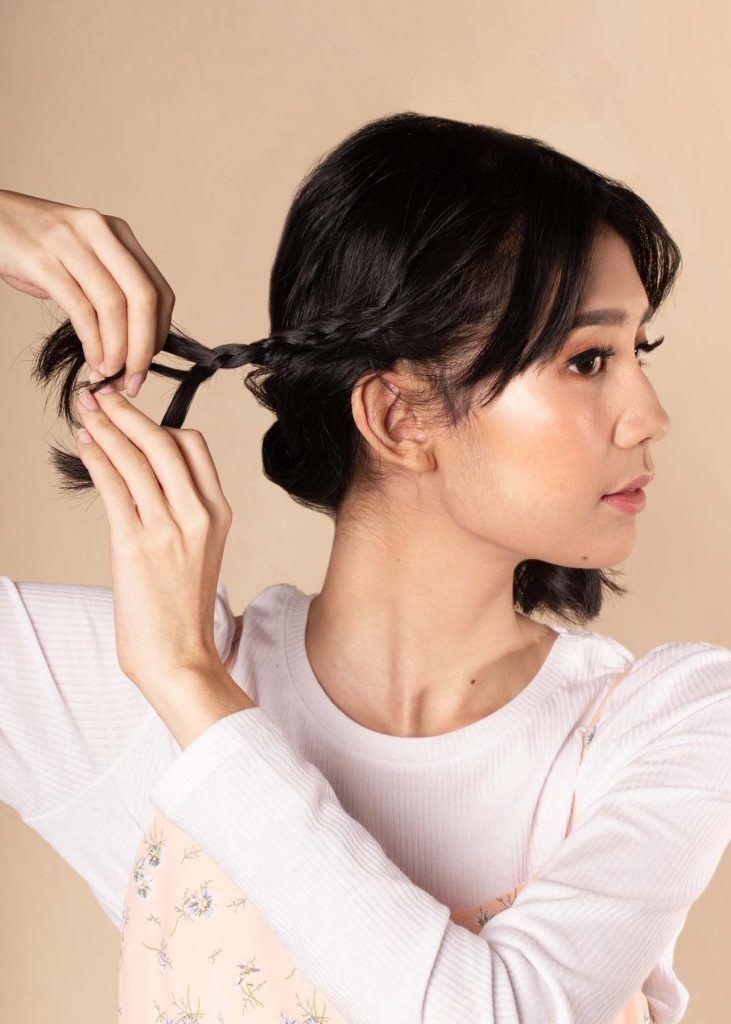 ผู้หญิงเอเชียผมสั้น ใส่เสื้อสีชมพูอ่อน กำลังเกล้าผม