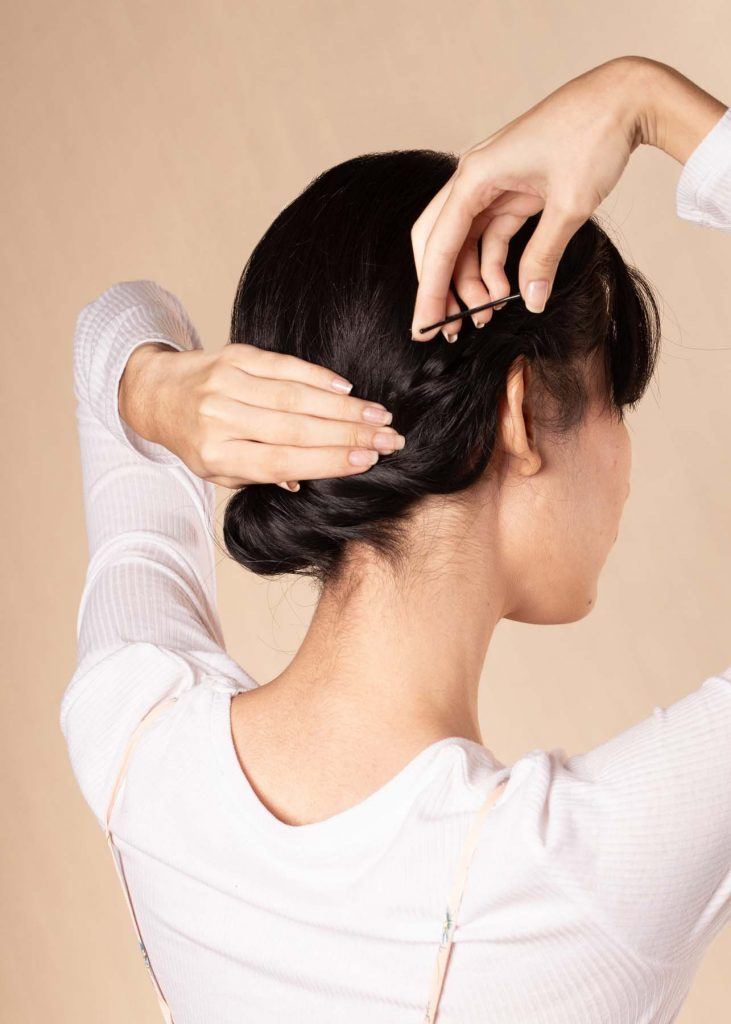 ผู้หญิงเอเชียผมสั้น ใส่เสื้อสีชมพูอ่อน กำลังเกล้าผม