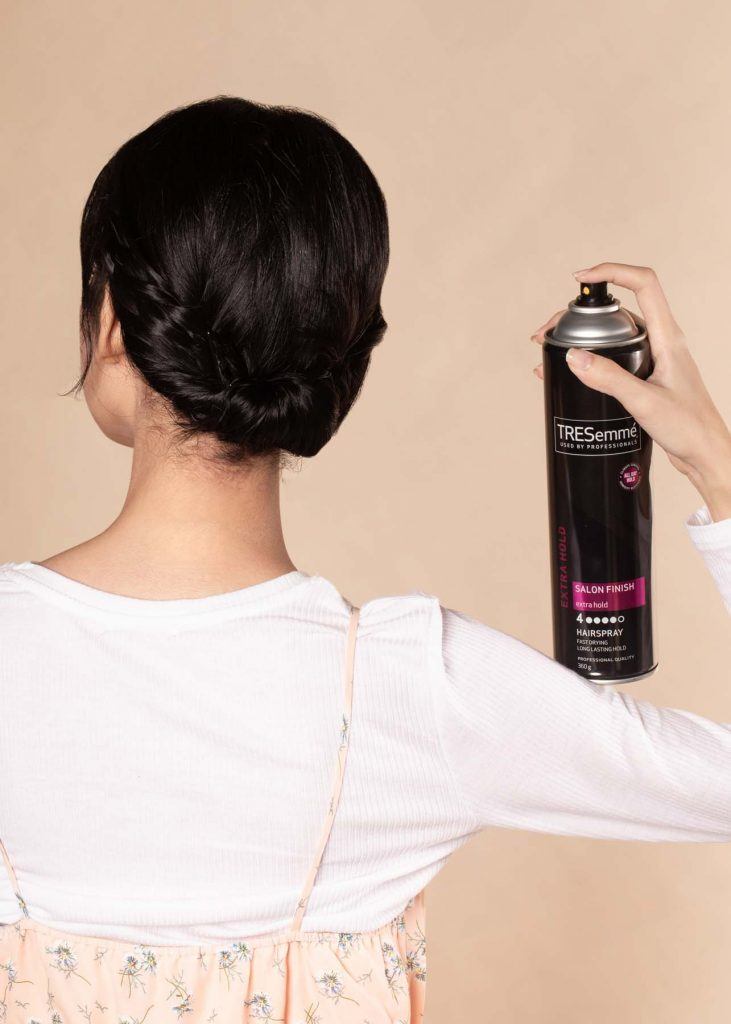 ผู้หญิงเอเชียผมสั้น ใส่เสื้อสีชมพูอ่อน กำลังฉีดสเปรย์ผม