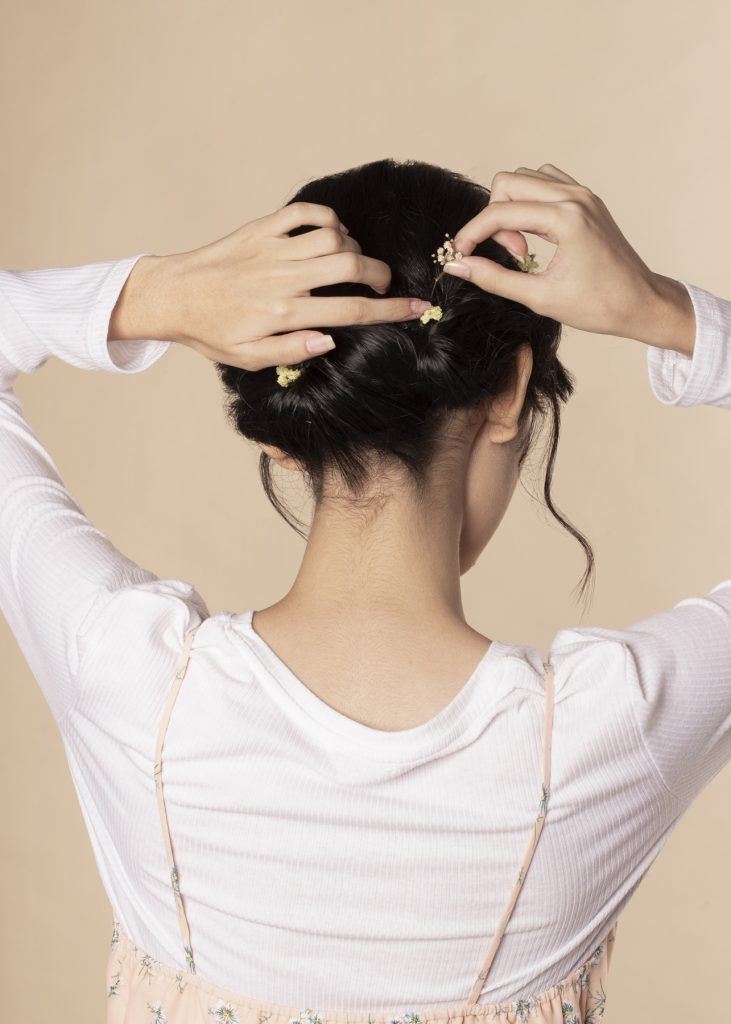 ผู้หญิงเอเชียผมสั้น ใส่เสื้อสีชมพูอ่อน กำลังเกล้าผม