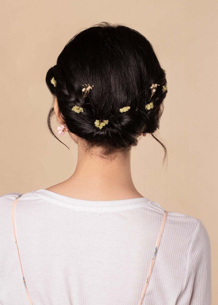 ผู้หญิงเอเชียผมสั้น ใส่เสื้อสีชมพูอ่อน ทำทรงผมเกล้าประดับด้วยดอกไม้ดอกเล็กๆ