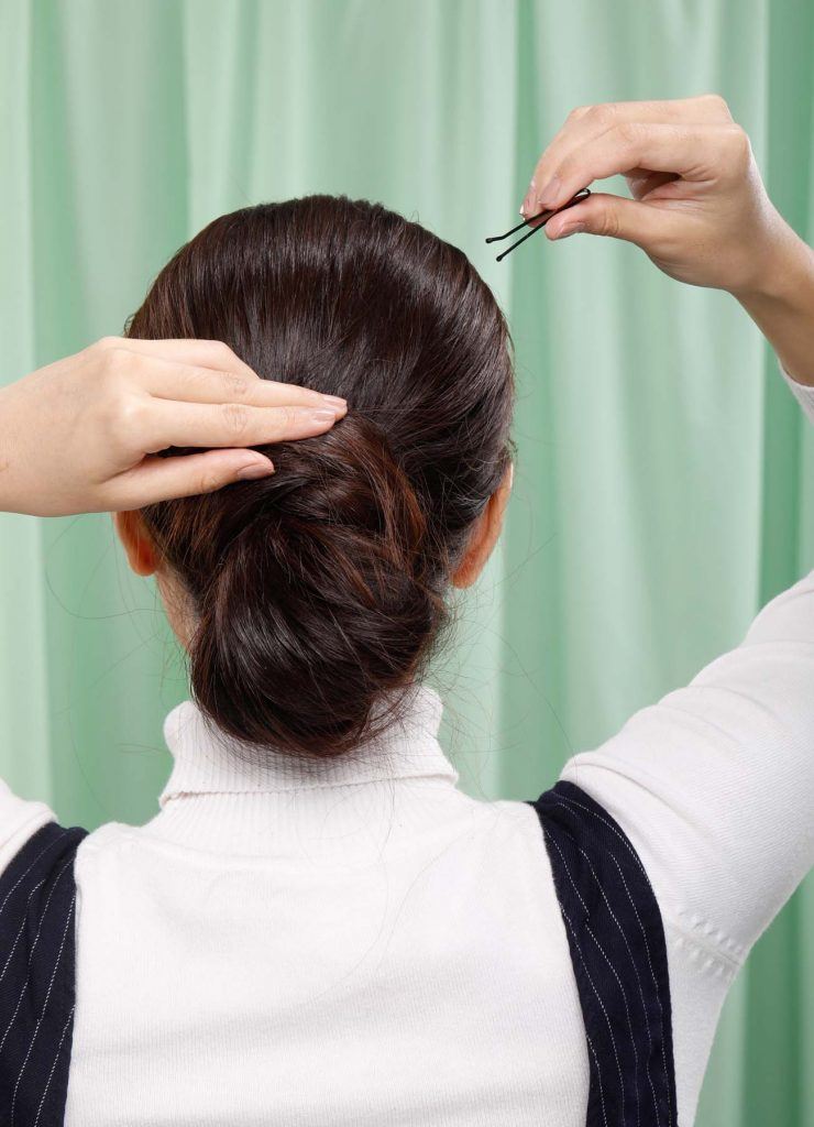 ผู้หญิงเอเชียผมยาวสีดำ กำลังเกล้าผมและติดกิ๊บ