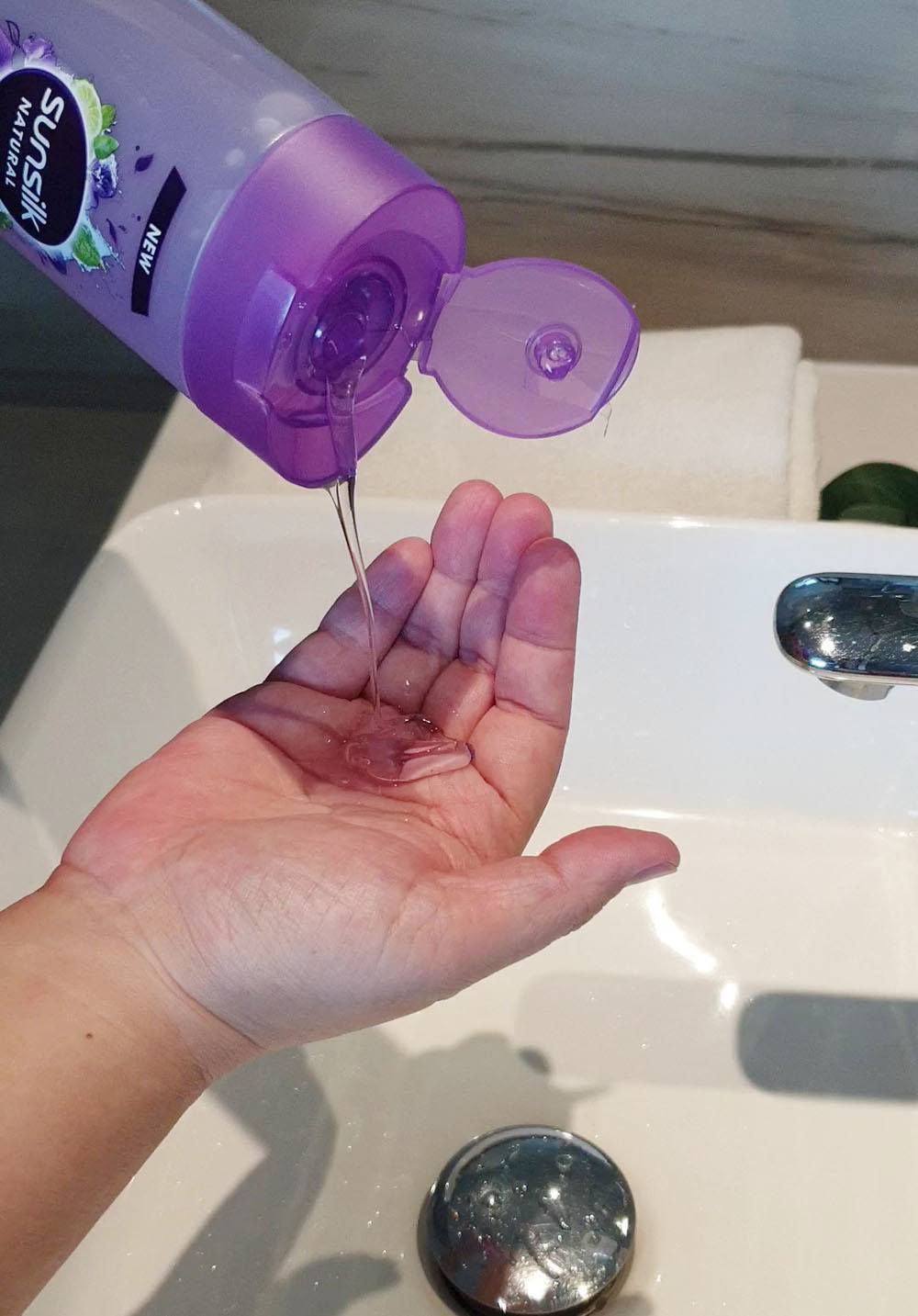 ผู้หญิงกำลังเทแชมพูใส่มือ ซันซิล เนเชอรัล สูตรใหม่