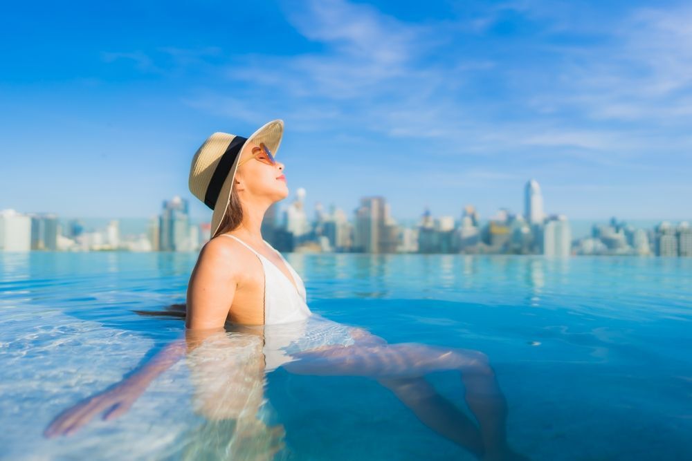 หญิงสาว ผิวขาว สวมหมวกปีก ใส่แว่นดำ แช่น้ำ ในสระว่ายน้ำ กลางแจ้ง