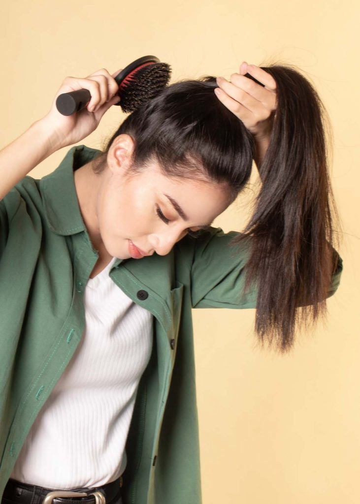 ผู้หญิงเอเชียผมยาว ใส่เสื้อเชิ้ตสีเขียว ใช้หวีรวบผมเป็นหางม้า