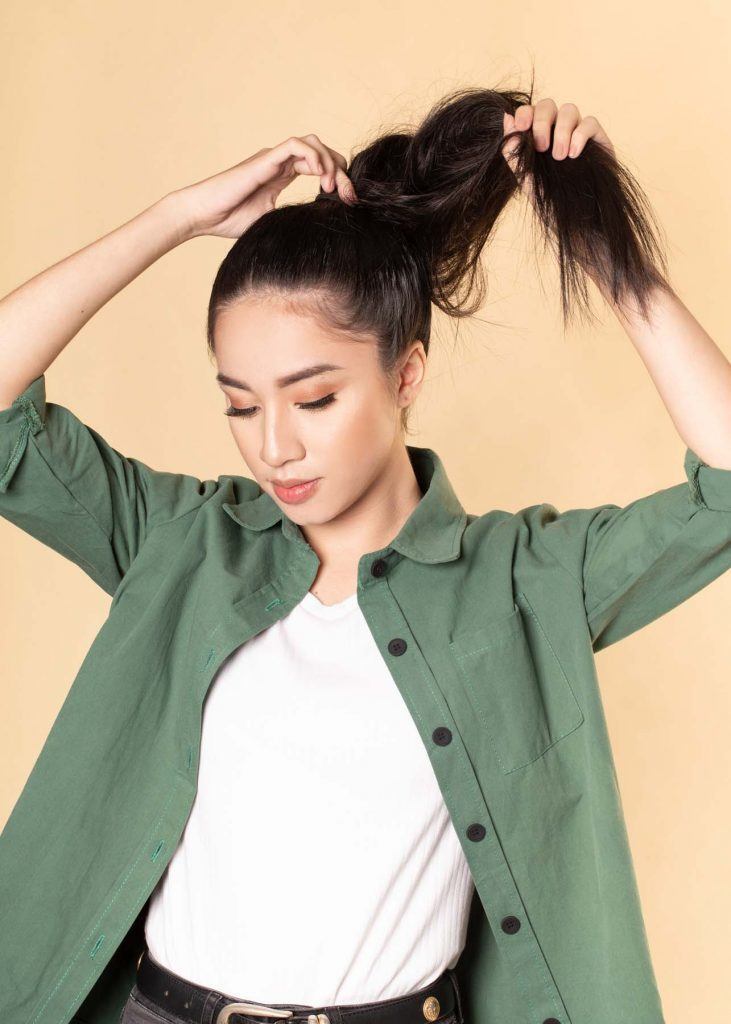 ผู้หญิงเอเชียผมยาว ใส่เสื้อเชิ้ตสีเขียว สาธิตวิธีทำผมทรงดังโงะ
