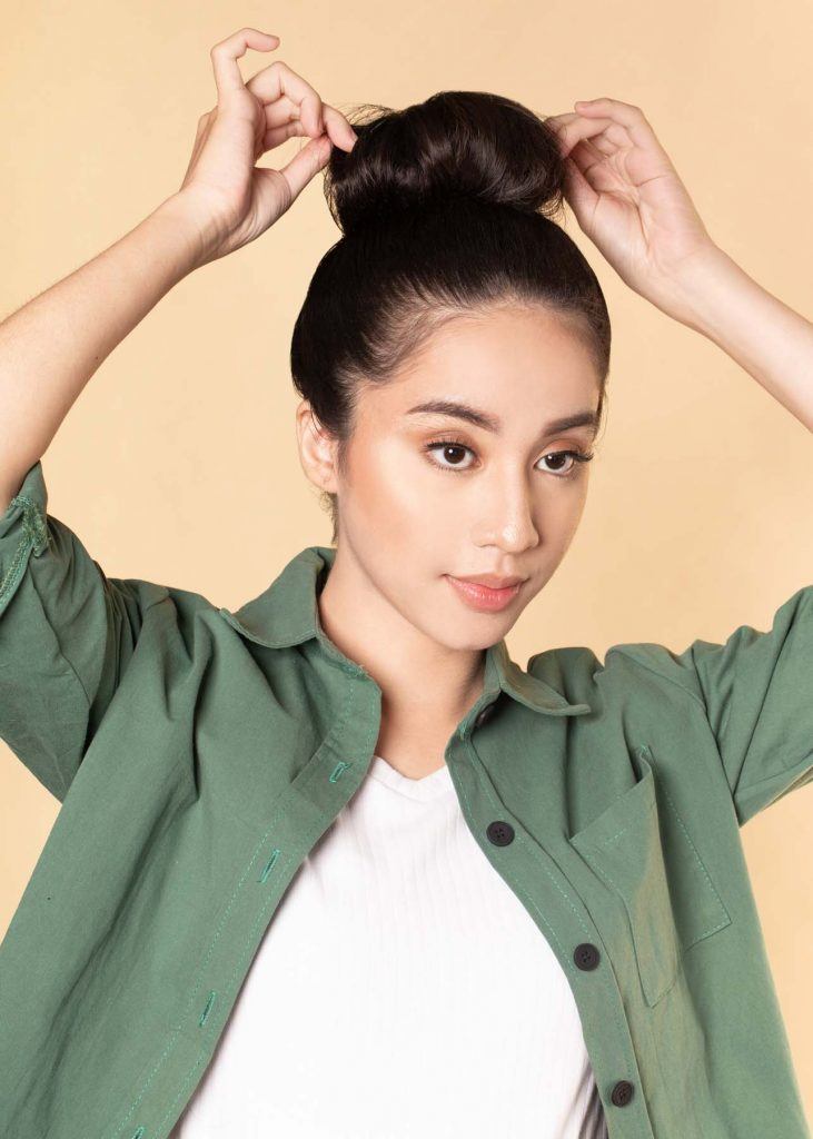 ผู้หญิงเอเชียผมยาว ใส่เสื้อเชิ้ตสีเขียว สาธิตวิธีทำผมทรงดังโงะ
