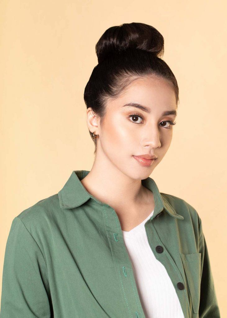 ผู้หญิงเอเชียผมยาว ใส่เสื้อเชิ้ตสีเขียว สาธิตวิธีทำผมทรงดังโงะ