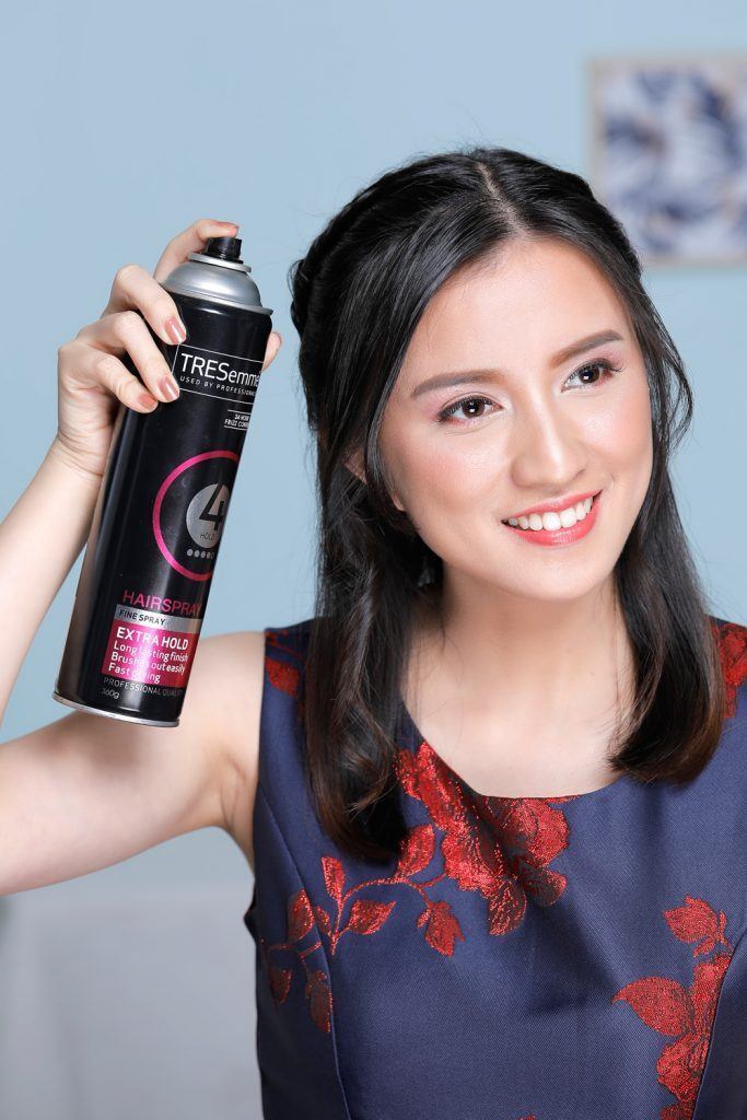 ผู้หญิงเอเชียผมยาวประบ่า กำลังฉีดสเปรย์แต่งผม