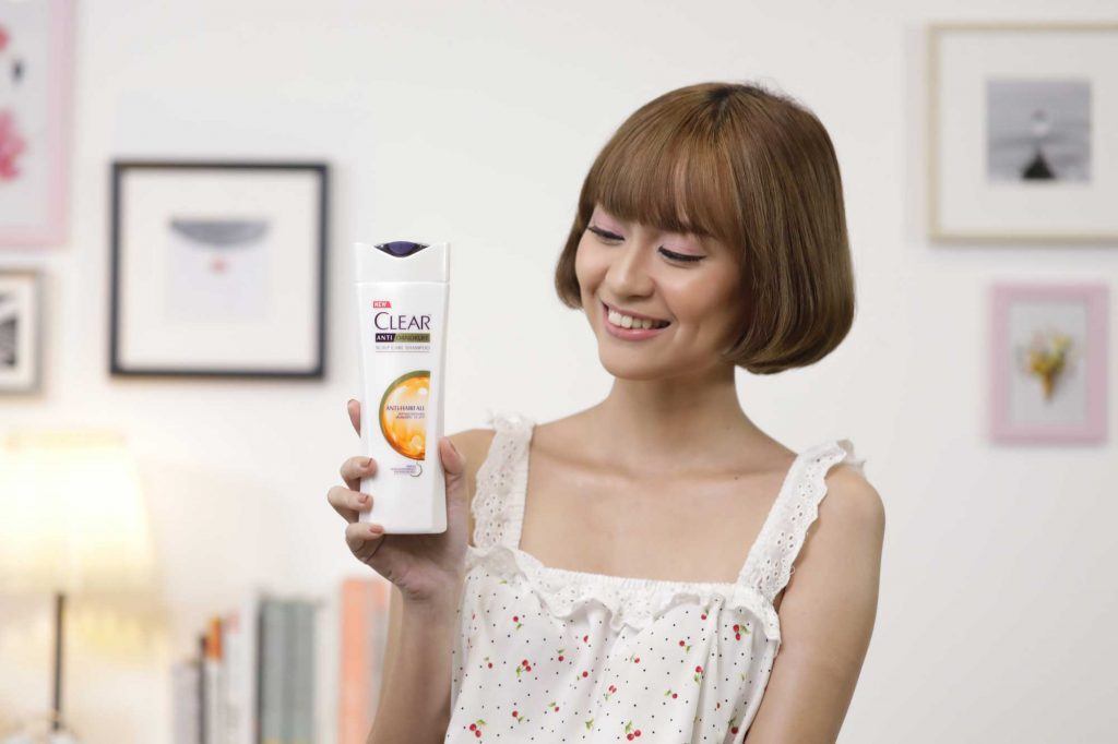 ผู้หญิงเอเชีย หน้าม้าผมสั้น ถือขวดแชมพู