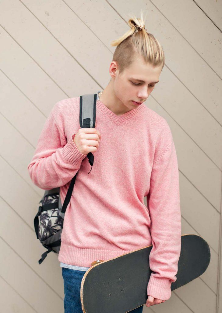 นายแบบ ฝรั่งชาย ผมสีบลอนด์ ถือสเก็ตบอร์ด สะพายเป้ ไว้ผมแมนบัน และตัดอันเดอร์คัต