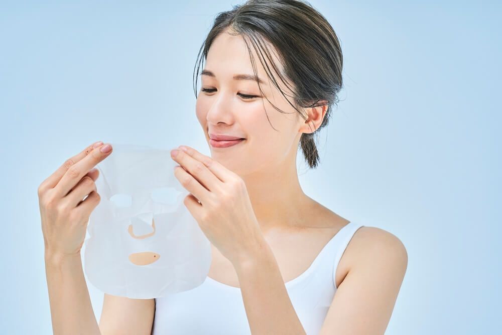 หญิงสาวรวบผมถือมาสก์ชีตสำหรับมาสก์หน้า