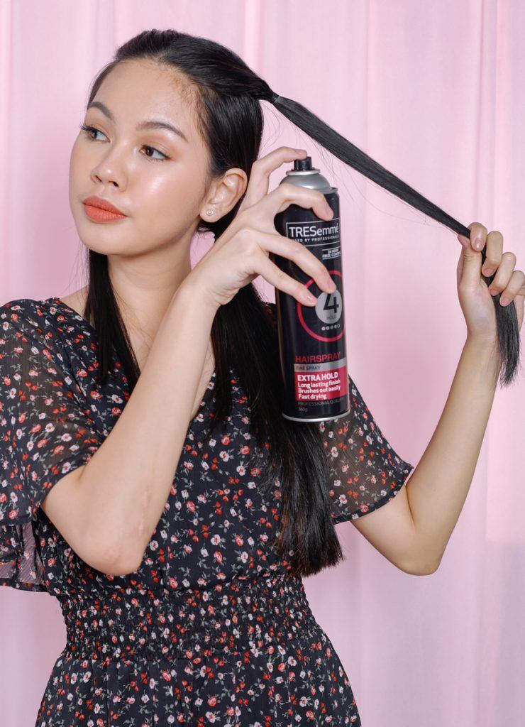 ผู้หญิงเอเชียผมยาวสีดำ กำลังฉีดสเปรย์ลงบนผม