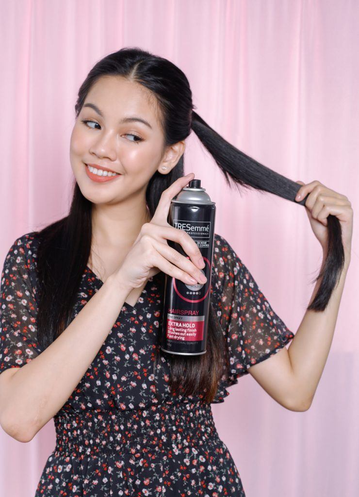 ผู้หญิงเอเชียผมยาวสีดำ กำลังฉีดสเปรย์ลงบนผม