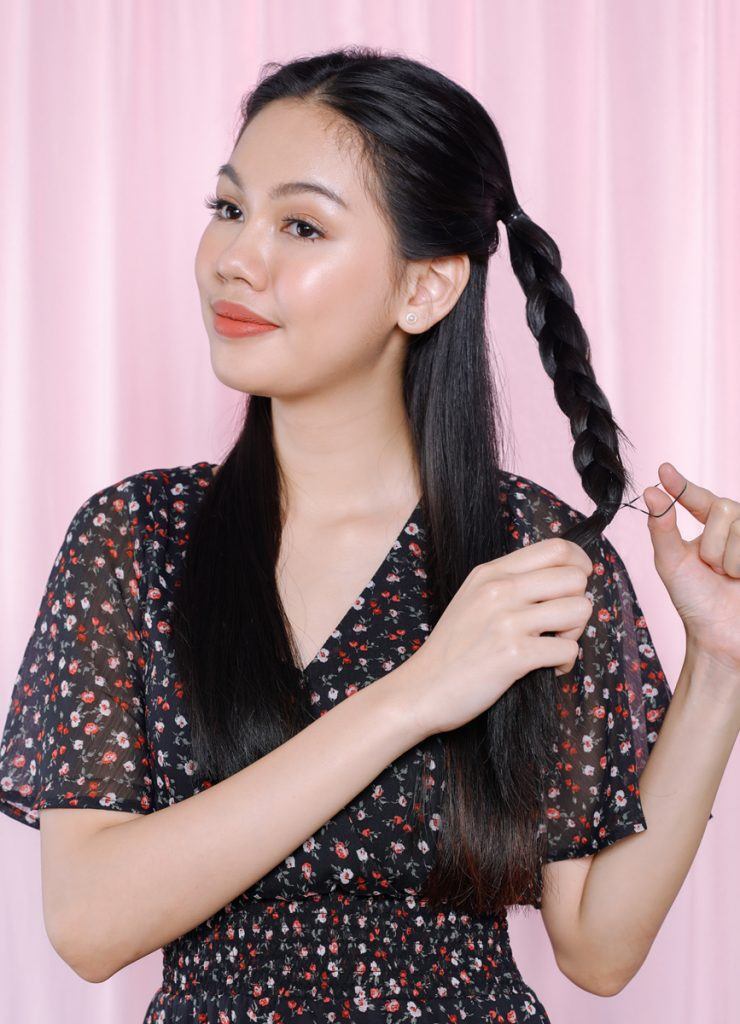 ผู้หญิงเอเชียผมยาวสีดำ กำลังถักผมเปีย