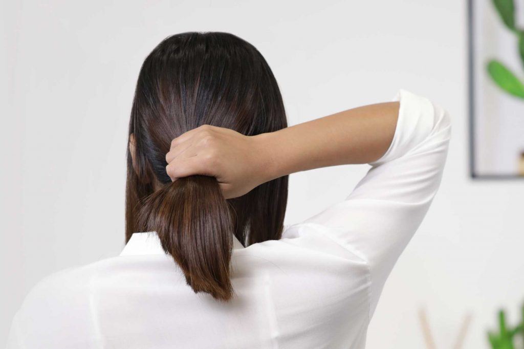 ผู้หญิงเอเชียผมยาวประบ่าสีดำ กำลังรวบผมหางม้า