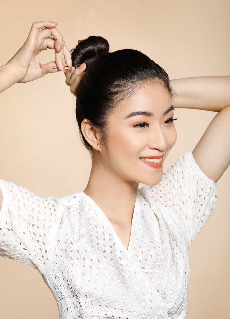 ผู้หญิงเอเชียผมยาวสีดำ กำลังเกล้าผมบัน