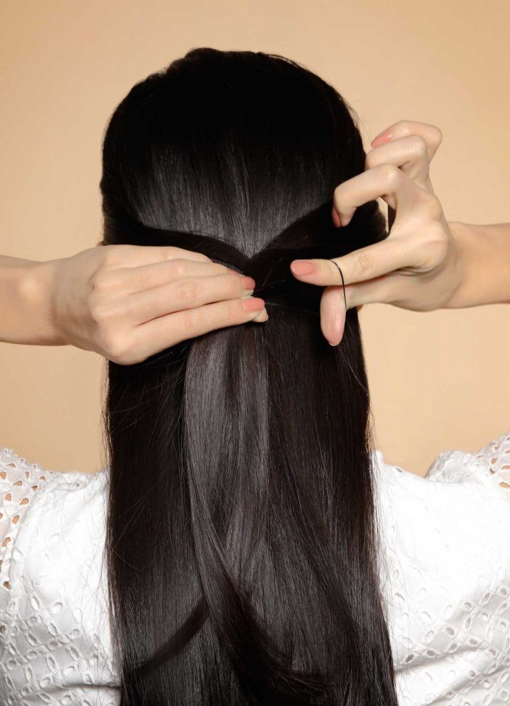 ผู้หญิงเอเชียผมยาวสีดำ กำลังมัดผมครึ่งหัว