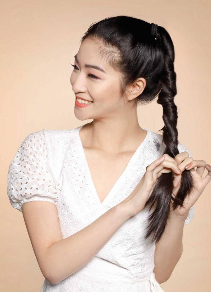 ผู้หญิงเอเชียผมยาวสีดำ กำลังไขว้ผมให้เป็นเกลียว