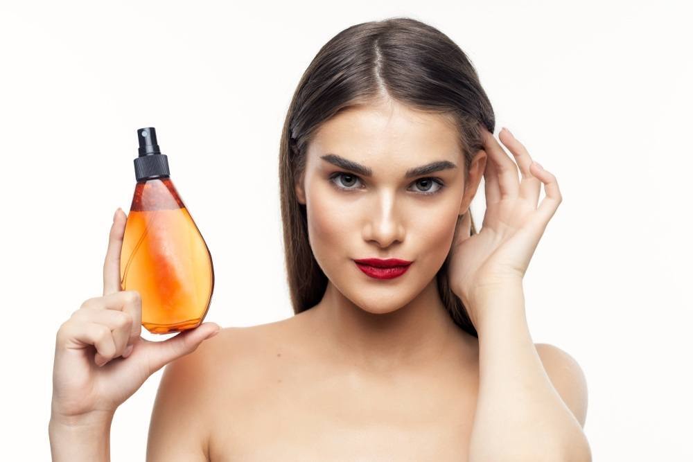 ผู้หญิงผมยาวถือขวดสเปรย์สำหรับฉีดผม