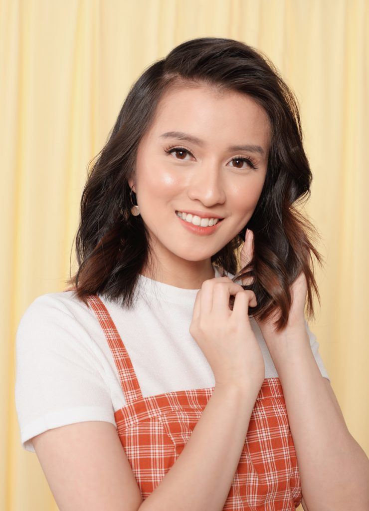 ผู้หญิงเอเชียไว้ผมประบ่าสีน้ำตาลเข้ม กำลังสางผมลอน