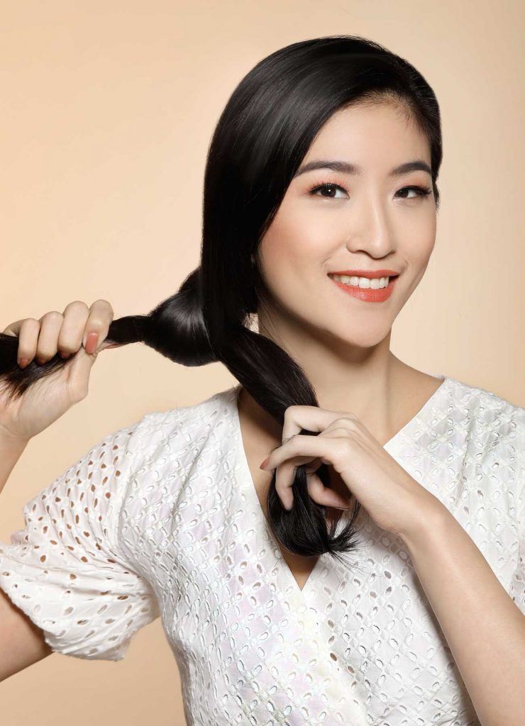 ผู้หญิงเอเชียผมยาวสีดำ กำลังผูกผม