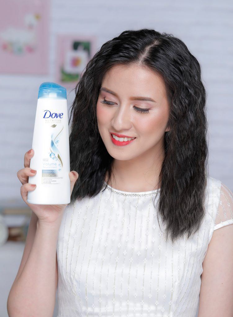 ผู้หญิงเอเชียผมหยักศกยาวประบ่า กำลังถือขวดแชมพูโดฟ