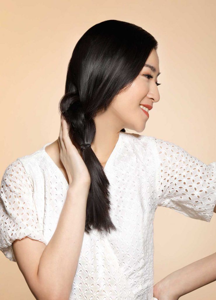 ผู้หญิงเอเชียผมยาวสีดำ กำลังจับผมหันข้าง